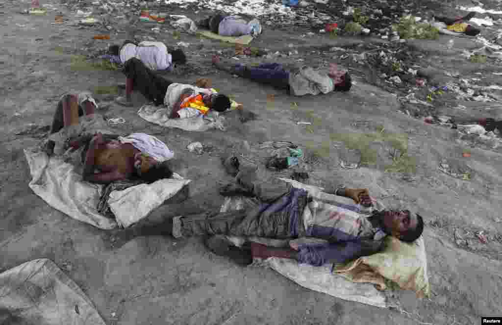 People sleep on the Yamuna River bed under a railway bridge during a hot summer day in the old quarter of Delhi, India, May 31, 2015.&nbsp;