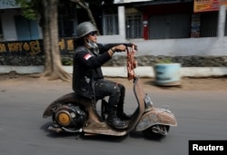 Seorang penggemar ekstrem Vespa mengendarai skuter Vespa setelah mengikuti festival Vespa ekstrem di Semarang, 22 Juli 2018.