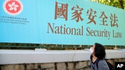 香港一名妇女走过街头的国安法宣传牌。（2020年6月30日）