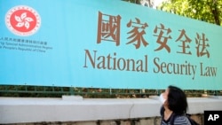香港一名婦女走過街頭的國安法宣傳牌。（2020年6月30日）