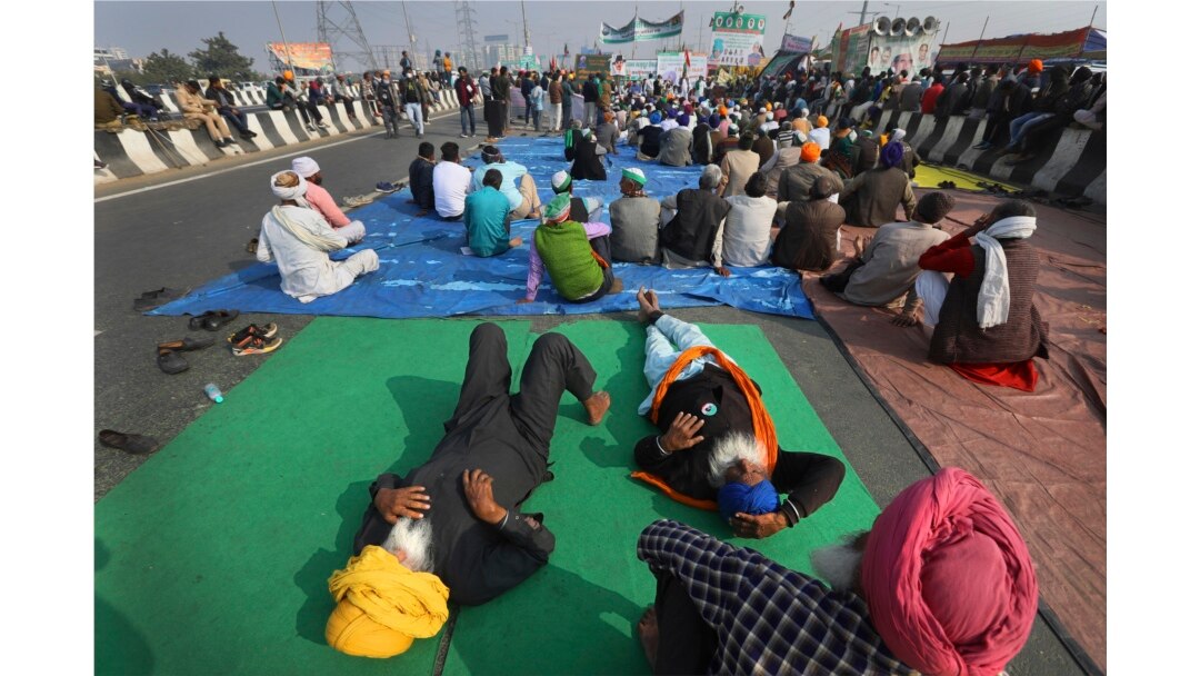 Petani India mendengarkan pembicara saat mereka memblokir jalan raya saat melakukan aksi protes terhadap undang-undang pertanian baru di New Delhi, India, Senin, 21 Desember 2020.