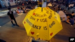 FILE - An umbrella, which has become an icon of the protest, reads pro-democracy messages above the student-led protest site in the Mong Kok district of Hong Kong, Monday, Oct. 20, 2014.