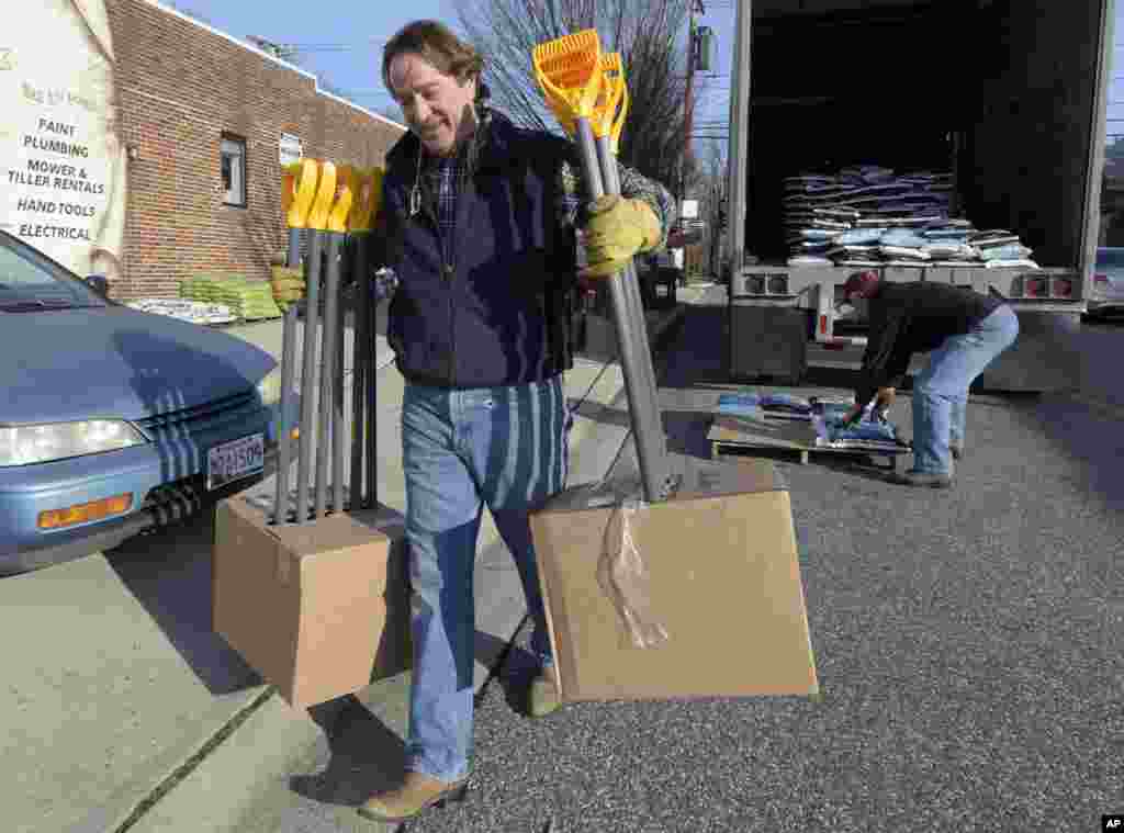 Vincent Ayd, kiri, pemilik Ayd Hardware di Towson, Maryland, dan pengemudi truk Mike Jock, dari Newark, Deleware, menurunkan sekop salju di Towson, 21 Januari 2016.