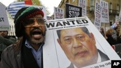 Seorang demonstran memegang gambar Presiden Susilo Bambang Yudhoyono selama unjuk rasa di depan tempat tinggal Perdana Menteri Inggris David Cameron, London. (AP/Lefteris Pitarakis)
