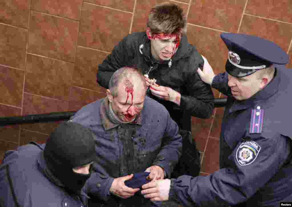 Interior Ministry members stand near men who were injured in clashes between pro-Russian and pro-Ukrainian supporters during rallies in Kharkiv, Ukraine, April 13, 2014.