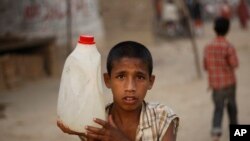 Un niño lleva un contenedor de agua recogida de un grifo público en Islamabad, Pakistán, junio 22 de 2018.