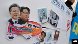 Pictures of South Korean President Moon Jae-in and North Korean leader Kim Jong Un are seen on a sign during a rally to denounce the U.S. policy against North Korea in Seoul, South Korea, Jan. 16, 2018