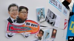 Pictures of South Korean President Moon Jae-in, left, and North Korean leader Kim Jong Un are seen on a sign during a rally to denounce the United States' policy against North Korea and demand the peaceful Winter Olympics in Seoul, South Korea.