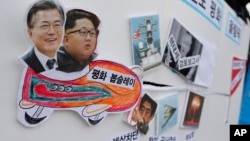 FILE - Pictures of South Korean President Moon Jae-in, left, and North Korean leader Kim Jong Un, second left, are seen on a sign during a rally to denounce the United States' policy against North Korea and demand the peaceful Winter Olympics in Seoul, South Korea.