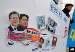Pictures of South Korean President Moon Jae-in (L) and North Korean leader Kim Jong Un (2nd-L) are seen on a sign during a rally to denounce the United States' policy against North Korea and demand the peaceful Winter Olympics in Seoul, South Korea, Jan. 16, 2018.