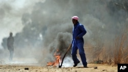 In this photo taken Monday, Sept 3, 2012, sacked gold miners set up a burning barracade at Gold One International's mine east of Johannesburg. 