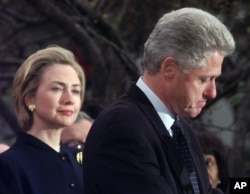 FILE - Then first lady Hillary Clinton watches her husband, President Bill Clinton, pause as he thanks those Democratic members of the House of Representatives who voted against his impeachment, Dec. 19, 1998. Clinton was impeached by the House but later aquitted in the Senate.