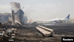 Beberapa unit pesawat terbang terlihat berada di dekat bangunan yang hancur di Bandara Internasional Jinnah pasca serangan militer Taliban di Karachi, Pakistan (10/6). 