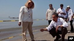 President Barack Obama and Lafourche Parish President Charlotte Randolf, left, inspect a tar ball as they look at the effect the BP oil spill is having on Fourchon Beach in Port Fourchon, Louisiana, May 28, 2010. (Official White House Photo by Chuck Kenne