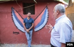 Ayad Nasser (left), talks to a local resident. Born in Ouzai in 1970, he has returned to the neighbourhood with artists and volunteers. (J. Owens for VOA)