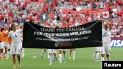 Jun 27, 2015; Vancouver, British Columbia, CAN; England midfielder Fara Williams (4) and midfielder Katie Chapman (16) raise a banner for Canada after the quarterfinals of the FIFA 2015 Women's World Cup at BC Place Stadium. England won 2-1. Mandatory Cre