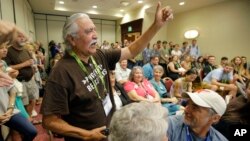 FILE - Willie Grayeyes, of the Utah Dine Bikeyah, raises his hand as he is recognized during a news conference, in Salt Lake City, Aug. 4, 2016. Navajo Nation leaders are protesting a Utah county's investigation into a Navajo candidate's residency, saying it's an attempt to disqualify a Native contender after a federal judge decided voting districts discriminated against Navajos.