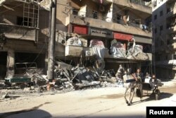 FILE - People ride in a cart pulled by a horse near the damaged al-Hakeem hospital, in a rebel-held part of Aleppo, Syria, Nov. 19, 2016.