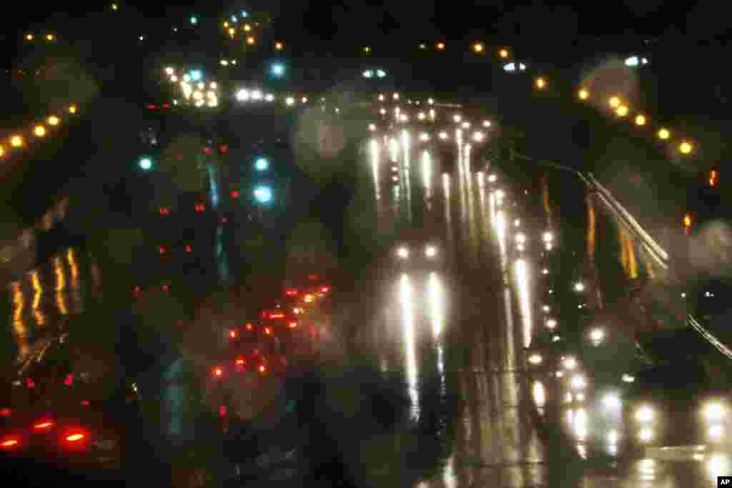 Reflected in the driver side mirror, motorists drive in the rain in Rockville, Maryland, Nov. 26, 2013, two days before the Thanksgiving holiday. 