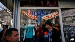 FILE - In this March 19, 2017 photo, Syrian refugees walk past stores with signs in Arabic and Turkish, in Gaziantep, southeastern Turkey.