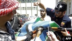 Các chiến binh phe nổi dậy hủy bỏ hình ảnh của nhà độc tài Gadhafi trong thủ đô Tripoli, Libya