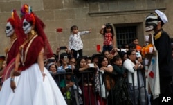 People watch a Day of the Dead parade in Mexico City, Sunday, Oct. 27, 2019. (AP Photo/Ginnette Riquelme)