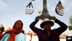 A protester from Boeung Kak lake holds a cutout of a scale symbolizing justice as she joins other villagers, who were allegedly evicted from their homes without adequate compensation, during a rally in front of the Justice Ministry in Phnom Penh, Cambodia, file photo. (AP Photo/Heng Sinith)