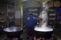 Seorang pekerja India mengaduk lidah buaya yang dimasak dalam kuali di kawasan tua New Delhi, 6 Desember 2018. (XAVIER GALIANA / AFP)