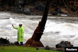 A Hawaii County employee photographs a river swollen by Hurricane Lane in Hilo, Hawaii, Aug. 25, 2018.