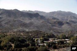 Burned down mountains tower over a residential neighborhood in the aftermath of a wildfire, Nov. 12, 2018, in Westlake Village, California.