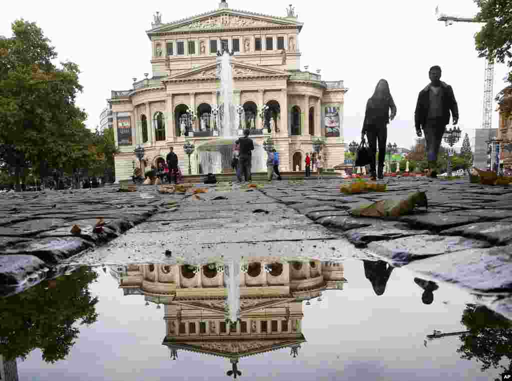 The Old Opera House is reflected in a small puddle in Frankfurt, Germany.