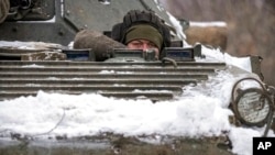 An Ukrainian serviceman peers from an armored personnel carrier near a front-line position in the Luhansk area, eastern Ukraine, Jan. 28, 2022.