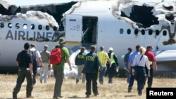 Para penyelidik dari Badan Keamanan Transportasi Nasional Amerika (NTSB) di lokasi kecelakaan pesawat Asiana Airlines Flight 214 di Bandar Udara San Francisco, Juli 2013.