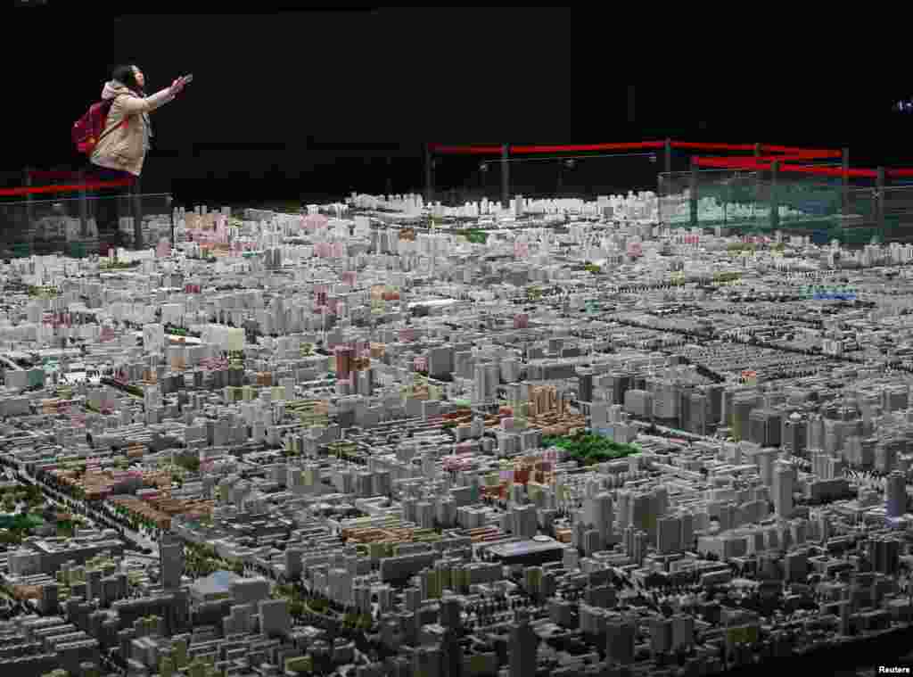 A visitor takes pictures of a model of Beijing's downtown at the Beijing Planning Exhibition Hall, a museum showcasing the achievement of Beijing urban planning construction, in Beijing, China, Nov. 5, 2013