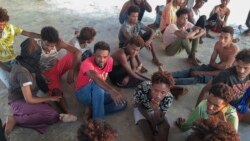 Rescued migrants sit on a coast some 100 kilometers (60 miles) east of Tripoli, Thursday, July 25, 2019, (Hazem Ahmed/AP)