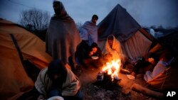 Migrants eat around a fire at a camp in Velika Kladusa, Bosnia, close to the border to Croatia, Nov. 18, 2018. 