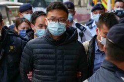 'Stand News' chief editor Patrick Lam is brought to the news outlet's office building in handcuffs after police were deployed to search the premises in Hong Kong's Kwun Tong district on Dec. 29, 2021.