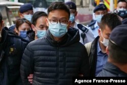 'Stand News' chief editor Patrick Lam is brought to the news outlet's office building in handcuffs after police were deployed to search the premises in Hong Kong's Kwun Tong district on Dec. 29, 2021.