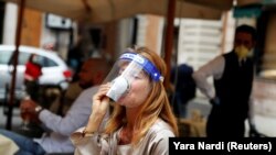 Žena sa zaštitnim vizirom pije kafu u kafiću u Rimu, 18. maja 2020. U Italiji su od ponedeljka dodatno olabavljene restriktivne mere uvedene zbog epidemije koronavirusa.