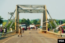 FILE - Two SPLA soldiers guard the bridge that divides South Sudan and Uganda, July 2016. (L. Paulat/VOA)