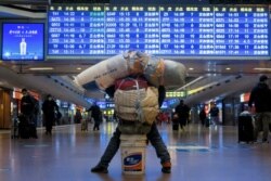 Seorang pelancong terlihat dengan barang-barangnya di stasiun kereta api, di tengah pandemi COVID-19, di Beijing, China 13 Januari 2021. (REUTERS / Thomas Peter)