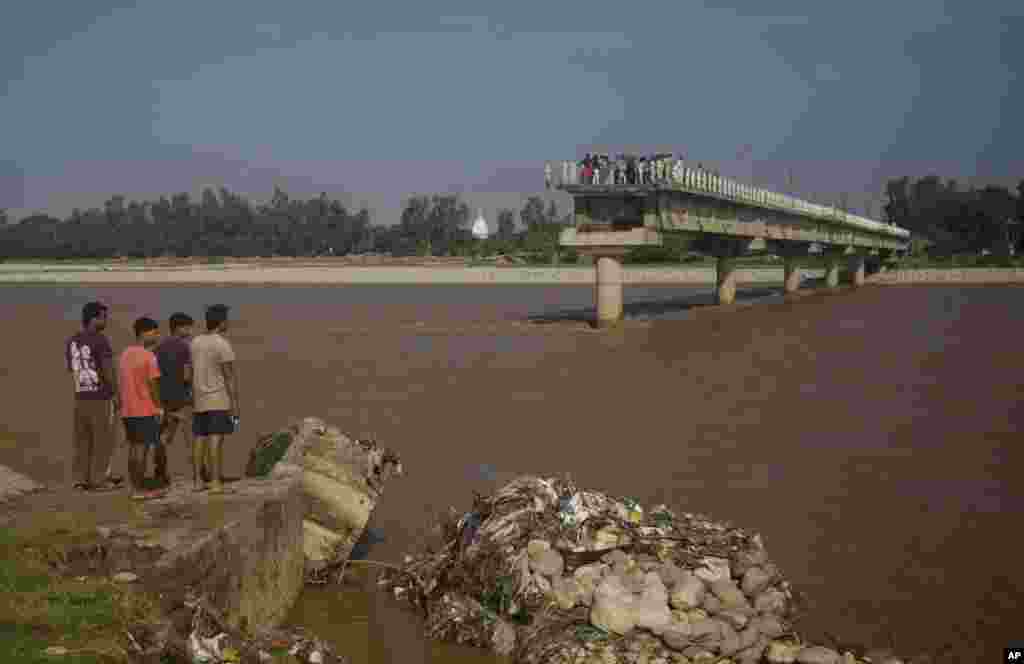 Orang-orang melihat jembatan di Sungai Tawi yang rusak akibat banjir di desa Mandal di pinggiran Jammu, India, 7 September 2014.