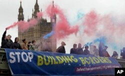 Demonstrators hold flares and a banner over Westminster Bridge in front of the Parliament buildings in London, Nov. 28, 2018. Campaigners from Another Europe is Possible and the Labor Campaign for Free Movement took part in a protest against Theresa May's Brexit deal.