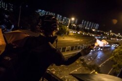 FILE - A protester throws a molotov cocktail to stop vehicles from passing through their road block beneath a bridge at the Chinese University of Hong Kong (CUHK), November 15, 2019.