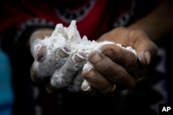 Hagar Yahia, a Yemeni woman, shows the amount of flour she uses to make a loaf of bread, in this Feb. 15, 2018 photo taken in Abyan, Yemen.