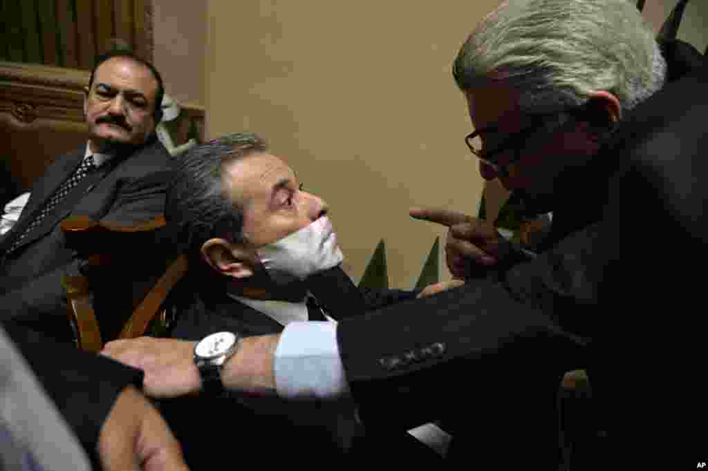 Tawfiq Okasha, a pro-government TV anchorman who was elected to parliament, is reprimanded by a fellow legislator after he taped his mouth shut in protest not being given the floor during a parliamentary session in Cairo, Egypt, Jan. 12, 2016.
