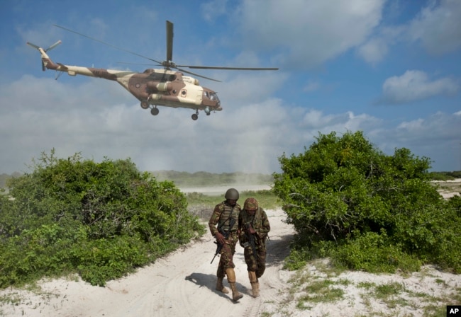 FILE - Two Kenyan army soldiers shield themselves from the downdraft of a Kenyan air force helicopter near the seaside town of Bur Garbo, Somalia, Dec. 14, 2011. A Kenyan military spokesman is categorically denying accusations that the Kenyan air force has been conducting airstrikes against Somali civilians.