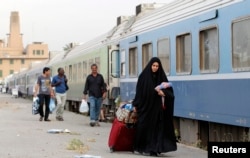 Passengers walk beside a train in a the rail station in Baghdad, May 6, 2013.