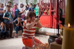 Seorang umat Buddha sedang berdoa sementara para tetangganya memperhatikan di Banda Aceh, 19 Februari 2015. (Foto: AFP)