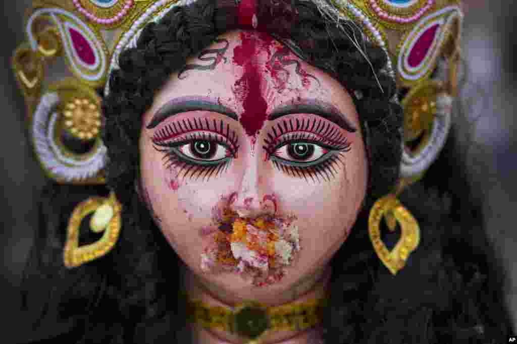 An idol of Hindu goddess Durga stands with vermillion paste smeared over its face and mouth stuffed with offerings, before it is immersed during Durga Puja festival in New Delhi, India.